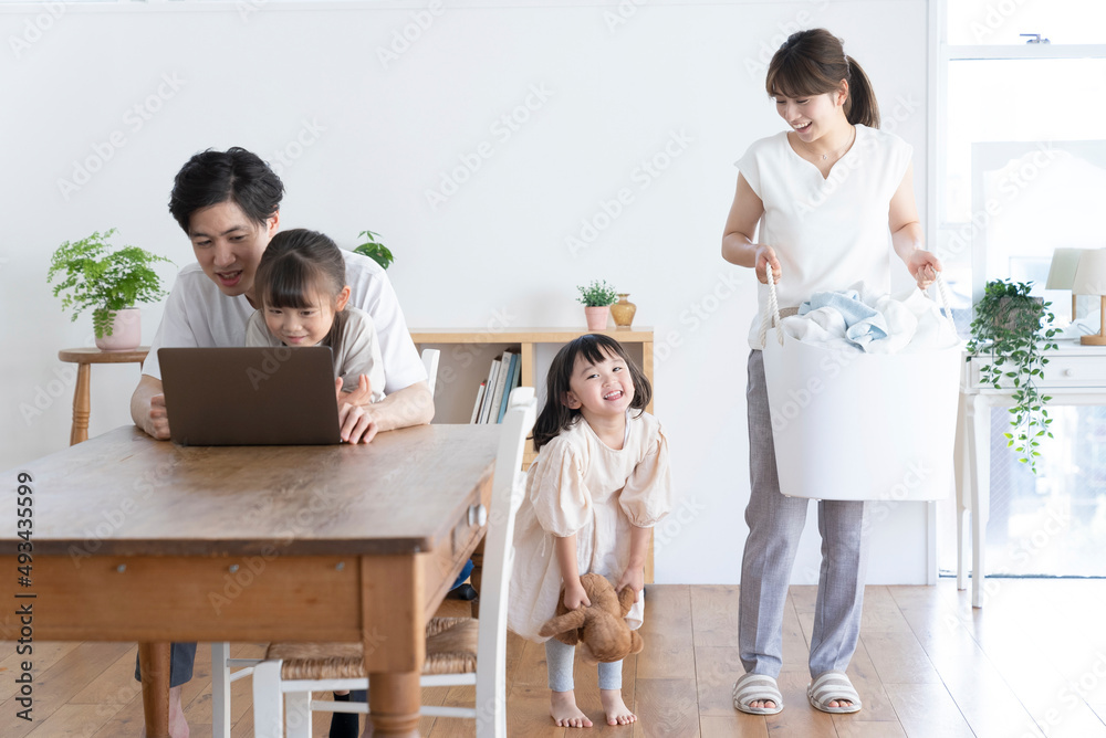 洗濯物を運ぶ母娘とパソコンを見る父子