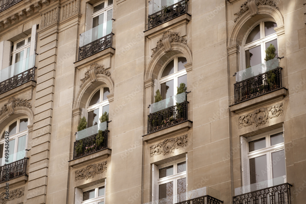 Beautiful facade of a building from Paris, France, with a lot of plants and elegant architecture details and decorations.