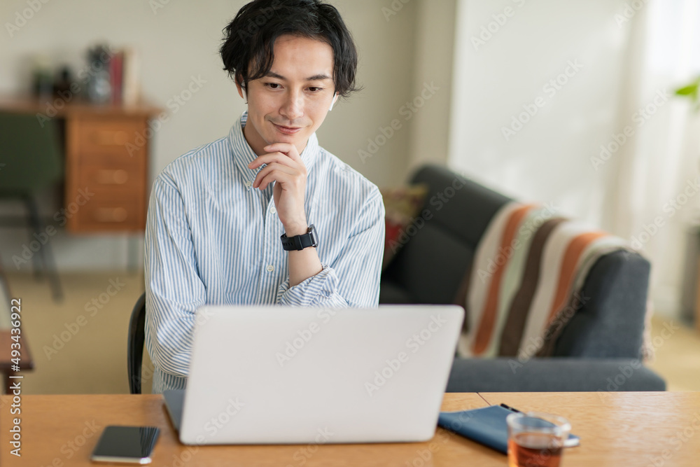 カジュアルな空間でノートPCの画面に向かって話しかける男性 カジュアルな空間でノートPCの画面に向かって話しかける男性
