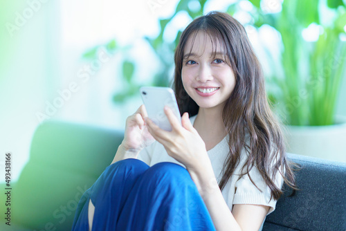 ソファに座ってスマートフォンを操作する女性 photo