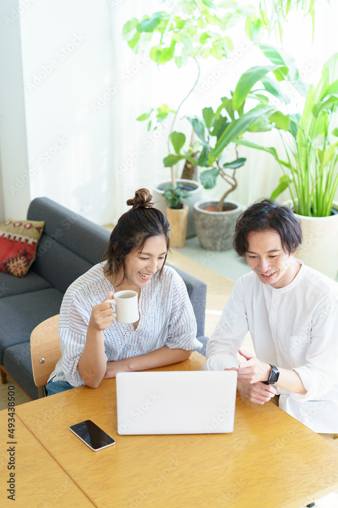 部屋でノートパソコンの画面を見る男女