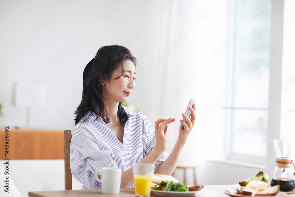 スマホを見ながら食事をする女性 スマホを見ながら食事をする女性