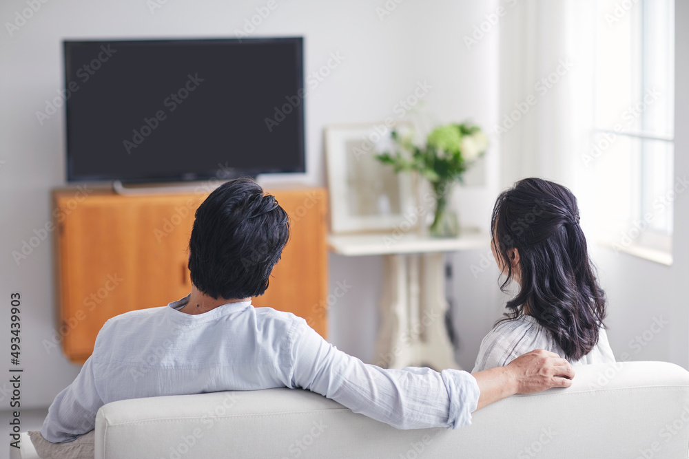 リビングでテレビを見ながらくつろぐ夫婦の後ろ姿 リビングでテレビを見ながらくつろぐ夫婦の後ろ姿
