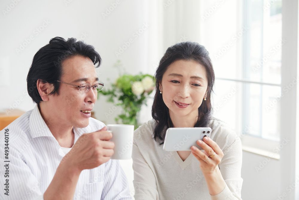 リビングでスマホを見る夫婦 リビングでスマホを見る夫婦