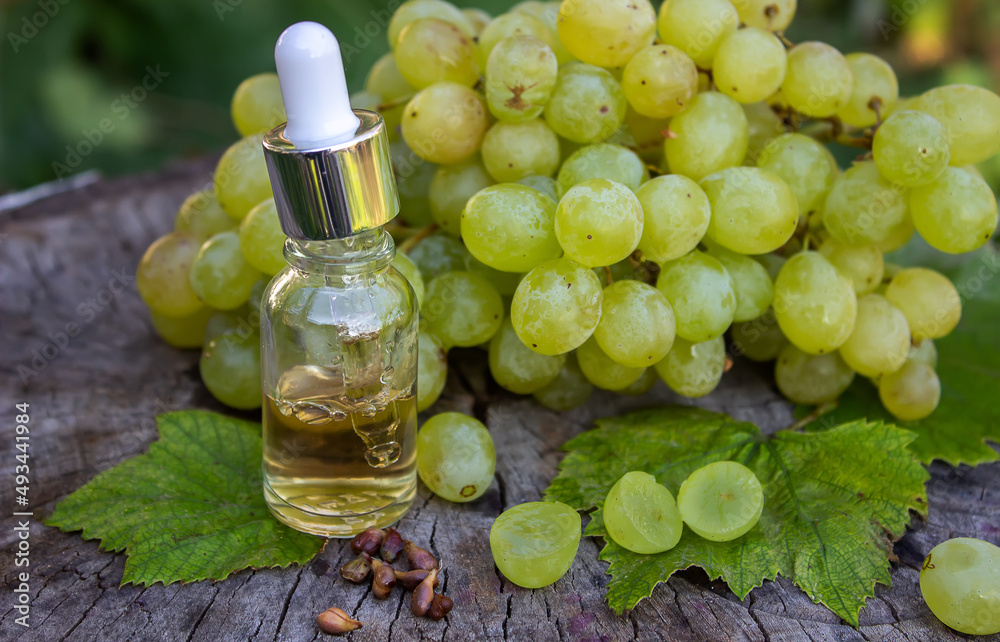 Grape seed oil in a glass jar and fresh grapes for spa and body care. The concept of spa, bio, eco products. Grape seed oil in a glass jar and fresh grapes for spa and body care. The concept of spa, bio, eco products.
