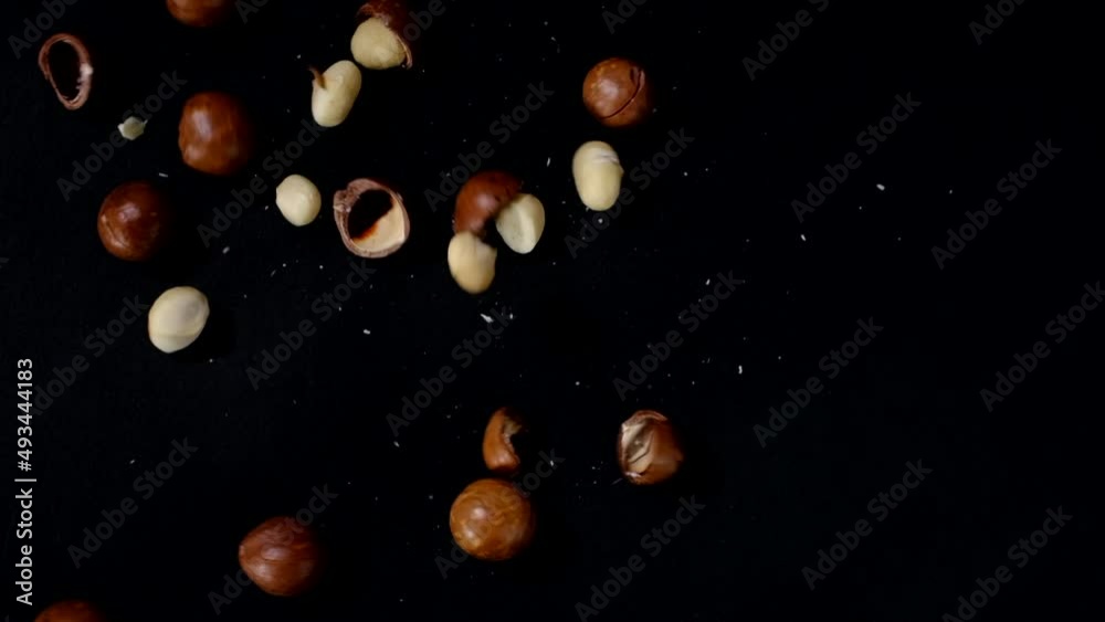 A closeup view of macadamia falling into black background for food advertising 
