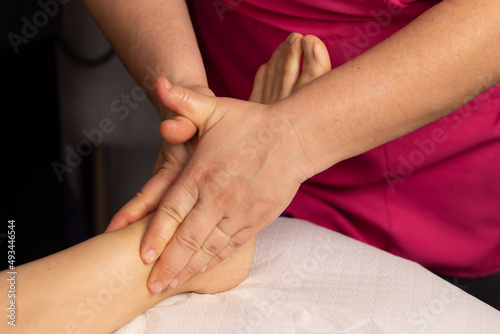 Close-up on the hands of the masseuse massaging a woman's bare foot