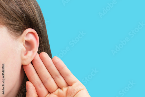 The girl listens attentively with her palm to her ear close up, news concept. photo