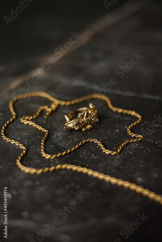 Gold ring in the shape of a crocodile with a gold chain on a dark marble background