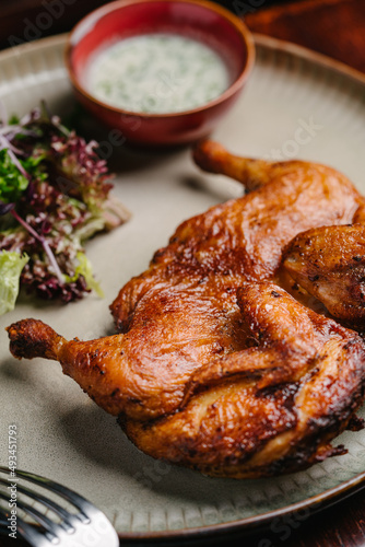 Grilled fried roast Chicken Tabaka with garlic sauce and salad on a wooden table