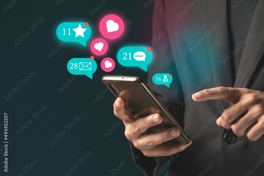 Person using a social media marketing concept on mobile phone with notification icons of like, message Person using a social media marketing concept on mobile phone with notification icons of like, message