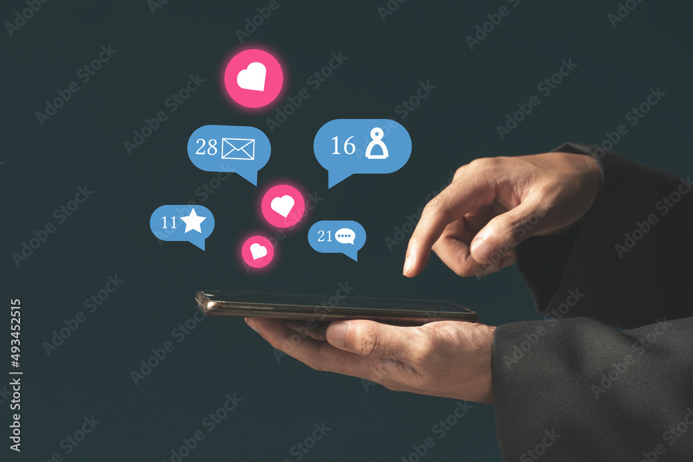 Person using a social media marketing concept on mobile phone with notification icons of like, message Person using a social media marketing concept on mobile phone with notification icons of like, message