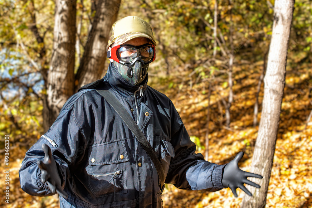 A man wearing a respirator mask and protective glasses in the forest at COVID-19 period.