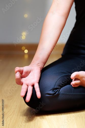 Close up shot of the hand and legs of an unrecognizable woman in relaxing position on a background with out of focus lights. Concept of health and wellness.