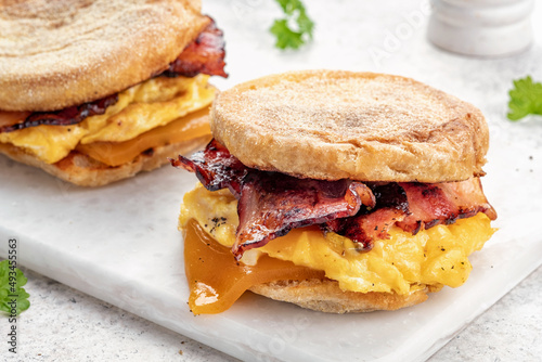 English muffin, egg, ham, and cheese breakfast sandwich on a cutting board