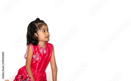 Smiling little girl sitting down on floor looking up, Isolated on white