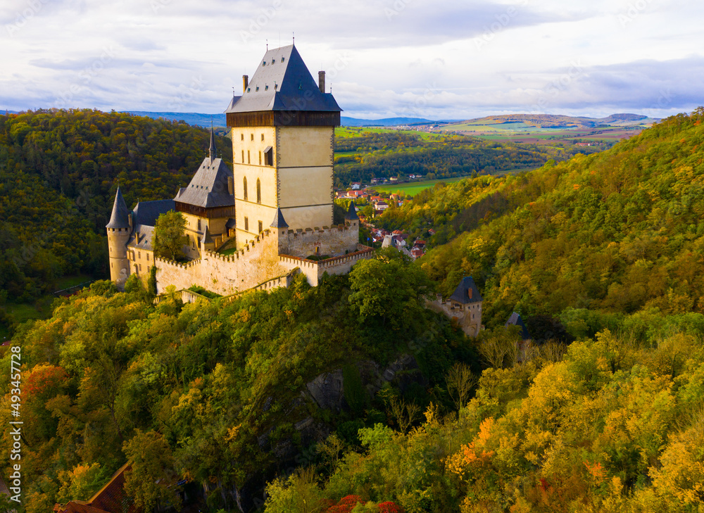 Aerial view of large Gothic Karlstejn Castle on top of hill against background of Czech village near Prague. 