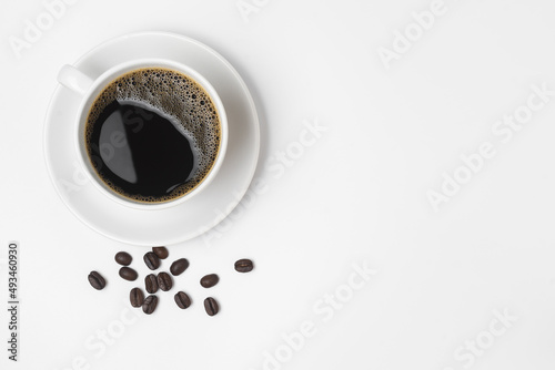 Black coffee in a cup and coffee beans isolated on a white background.