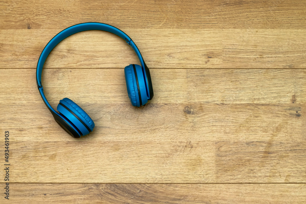 Blue Wireless Headphone Or Earphone on wooden table Blue Wireless Headphone Or Earphone on wooden table