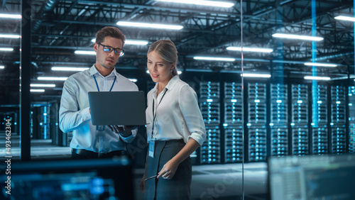 Female Chief Engineer Talks with Electronics Specialist, Explaining Things, While Works on Laptop Computer and Agrees with Her. Modern and Evening Office with Stylish Colleagues photo