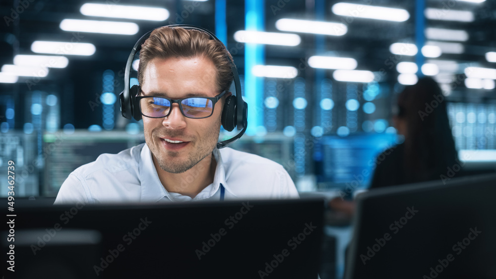 Serious Young Caucasian Man with Headset, Successful Manager of Call Center Sits in Office, Uses Computer, Talking on Video Conference with Client or Employee. Helpline Concept - obrazy, fototapety, plakaty 