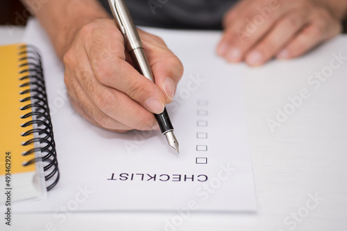 Close-up Of Person's Hand Marking On Checklist Form