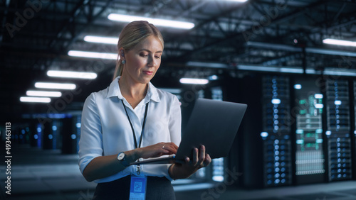 Portrait of Successful Female Chief Engineer or CEO Using Laptop Computer to Optimise Server Farm Cloud Computing Facility at the Evening Office. Cyber Security, Network Protection Concept photo