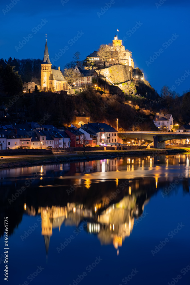Saarburg in Rhineland-Palatinate near Trier, Luxemburg is a small touristic town with medieval centre. Blue hour twilight atmosphere with lights, churches and ruined castle mirrored in River Saar.