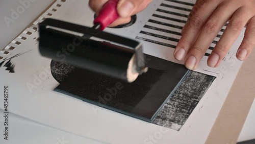 Woman using brayer roller with black ink for lino print photo