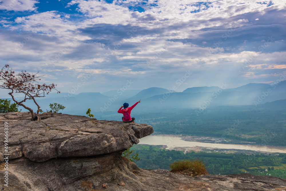 Young woman sitting on the cliff near  Mekong river, border of Thailand and Laos, Chana Dai Cliff, Ubon Rachathani province,Thailand.