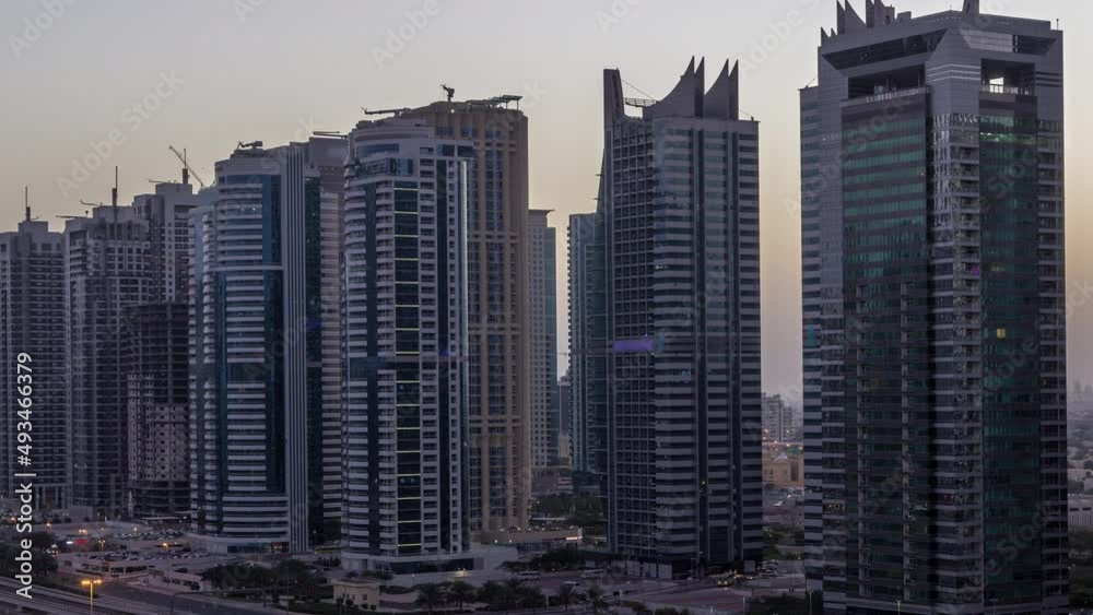 Aerial view of Jumeirah lakes towers skyscrapers night to day timelapse with traffic on sheikh zayed road.