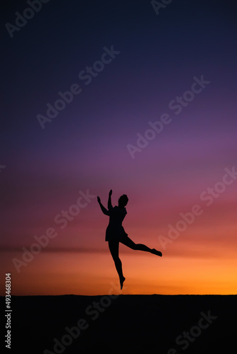 Girl Silhouette happy jumping on colorful sunset sky
