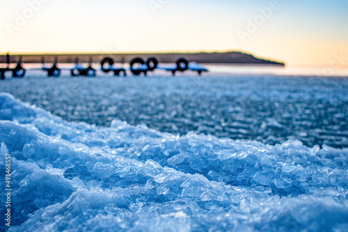 Pieces of ice on the background of the bridge and the hill, near the water