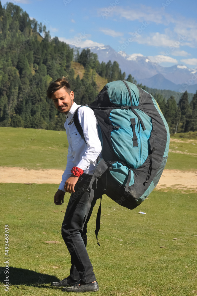 Rear view of a young male tourist walking with carrying parachute bag in the mountain 