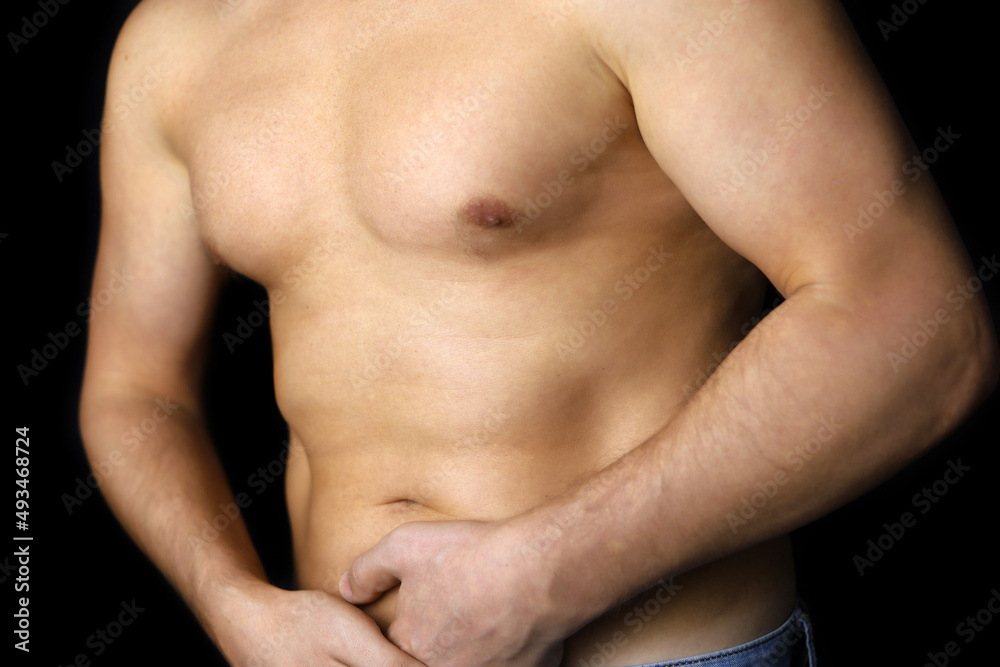 Muscular man suffering from abdomen pain, male torso on black background. Stomach diseases or pancreas inflammation