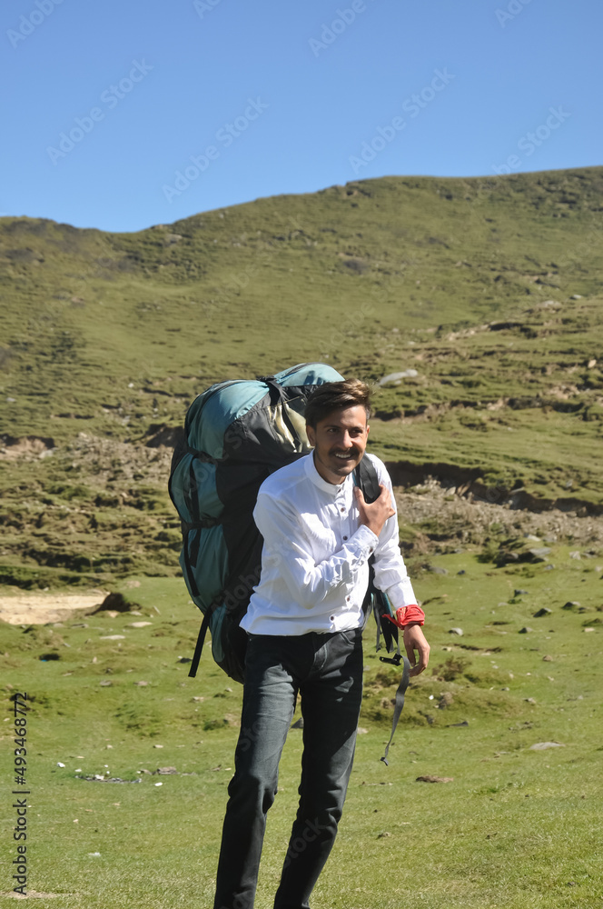 Obraz premium A cheerful young male tourist walking with carrying Parachute backpack in the mountain 