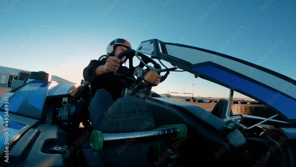 Low angle view of professional racer driving his go kart on a race track. Racer driving his kart on a race track. Racing in a fun competition on the  circuit at sunset