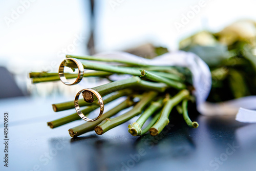 wedding rings on the stems of a bouquet of flowers