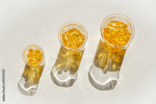 Foto Fish oil gelatin capsules in laboratory transparent flasks on a white background