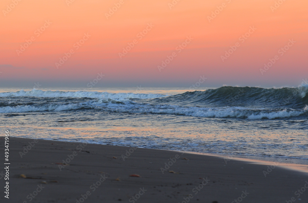 Coast with waves in sea on sunset. Waves in sea during storm and wind. Wave from the sea goes on land to the beach. Splashing Waves in ocean. Wave at Rising Storm near Seashore or Coastline. Seaside.