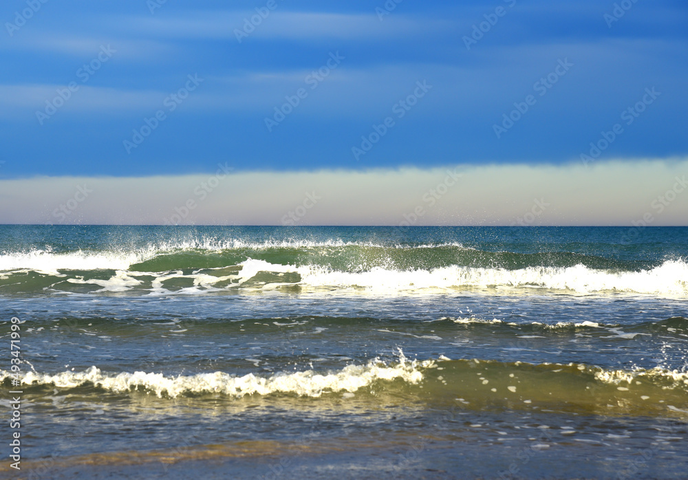 Waves in sea during a storm on sunset. Waves against backdrop of a stormy sky in sea. Waves at sea on dramatic sunset. Wave from the ocean goes on land to beach. Ocean during storm and wind. .