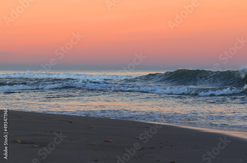 Fototapeta Naklejka Na Ścianę i Meble -  Coast with waves in sea on sunset. Waves in sea during storm and wind. Wave from the sea goes on land to the beach. Splashing Waves in ocean. Wave at Rising Storm near Seashore or Coastline. Seaside.