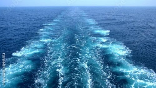 Wake of vessel. Wide wake trail from boat. Back view. Ocean water. Deep blue. Trace from large ship.