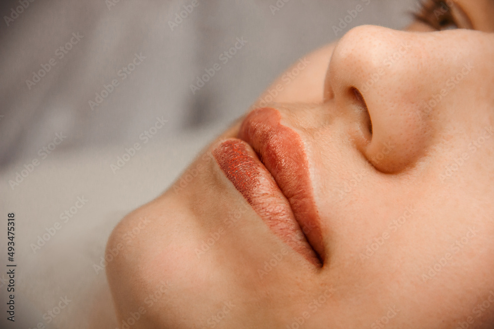Fototapeta premium intermediate result beauty procedure. closeup permanent lip tattoo. side view. beauty concept, free space