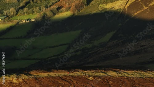 Mount Leinster, Carlow, Ireland, March 2022. Drone tracks along Rathnageeragh with a telephoto lens as hillwalkers enjoy the golden evening sunshine with farmland at Collasnagta in the background. photo