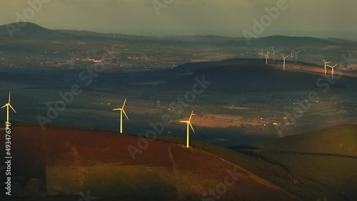 Kilbranish Wind Farm, Carlow, Ireland, March 2022. Drone gradually tracks west on a telephoto lens facing the hilltop wind turbines with Bunclody and county Wexford in the distance. photo