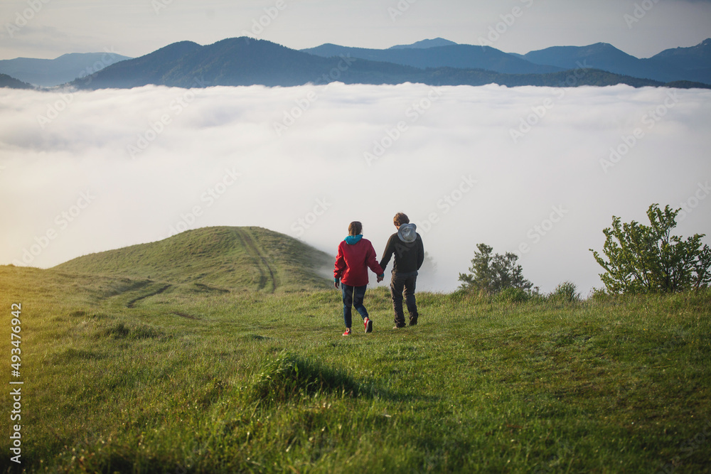 Young Couple Walks Holding Hands in Amazing Carpathian Misty Mountain Scenery Young Couple Walks Holding Hands in Amazing Carpathian Misty Mountain Scenery