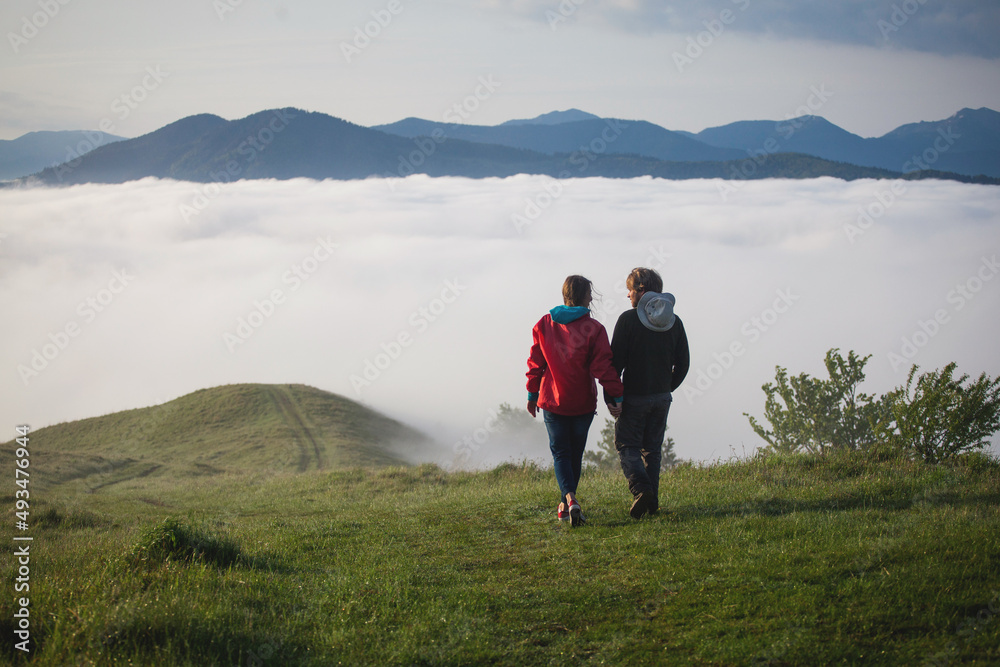 Young Couple Walks Holding Hands in Amazing Carpathian Misty Mountain Scenery Young Couple Walks Holding Hands in Amazing Carpathian Misty Mountain Scenery