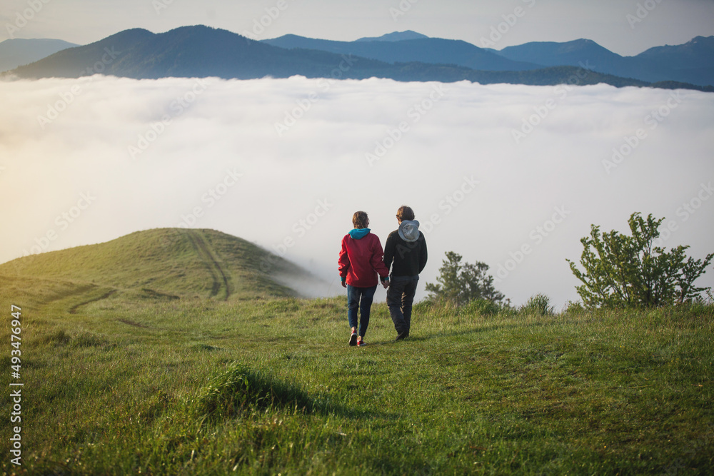 Young Couple Walks Holding Hands in Amazing Carpathian Misty Mountain Scenery
