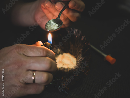 drug substance concept. guy with drugs on a spoon. the process of using hard drugs intravenously